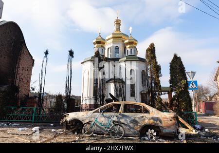 IRPIN, UKRAINE - Mar. 09, 2022: War in Ukraine. Chaos and devastation on the outskirts of Irpin. Damaged church and burned car as a result of the bombardment of a peaceful city Stock Photo