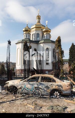 IRPIN, UKRAINE - Mar. 09, 2022: War in Ukraine. Chaos and devastation on the outskirts of Irpin. Damaged church and burned car as a result of the bombardment of a peaceful city Stock Photo