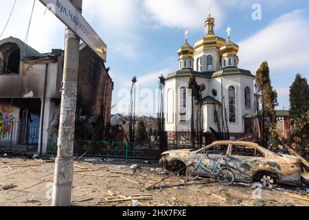 IRPIN, UKRAINE - Mar. 09, 2022: War in Ukraine. Chaos and devastation on the outskirts of Irpin. Damaged church and burned car as a result of the bombardment of a peaceful city Stock Photo