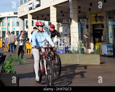 ASHKELON, ISRAEL - MARCH 04, 2022: a guy and a girl ride a bike along the embankment. Stock Photo