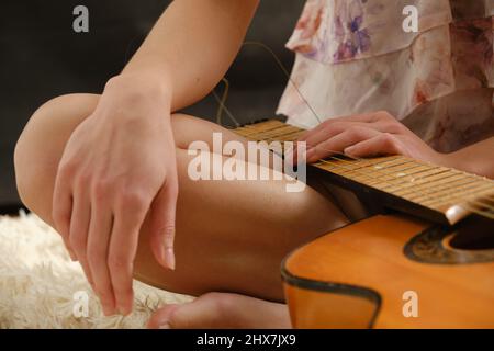 Broken guitar strings with female hands, guitar repair Stock Photo