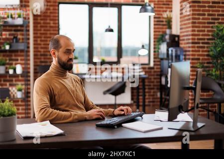 Business development agency office worker sitting in workspace while using computer. Marketing company financial consultant working on management plan for startup project. Stock Photo