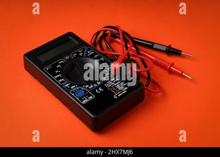 Black multimeter on orange background, close up Stock Photo