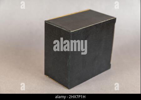 Rectangular black box on a gray background. Closed cardboard package with correct geometric shape. Stock Photo