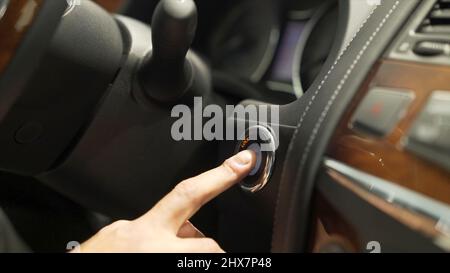 Close up for man finger pressing the car power start, stop button, transportation concept. Stock. Driver man hand pushing engine button of his car. Stock Photo