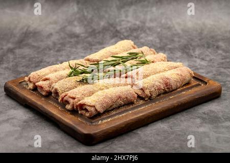 Beef schnitzel on dark background. Delicious raw meat schnitzel prepared with breadcrumbs and white sesame. Stock Photo