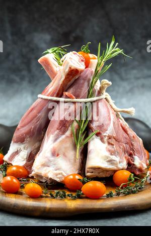 Raw lamb shank on dark background. Lamb shank on wood serving board Stock Photo