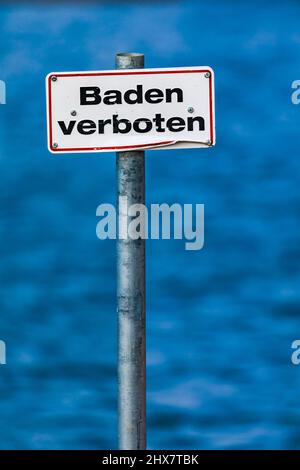 German no swimming sign on a pole isolated in front of a blue lake Stock Photo