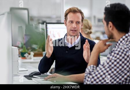 Sharing his knowledge. Coworkers in an office discussing a project. Stock Photo