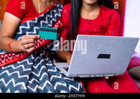 close up shot of mother and daughter making purchases online using credit card on laptop at home - concept of online bill payment and ecommerce Stock Photo
