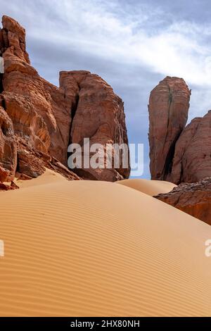Natural stones door  Low angle view perspective of a sand dune and rocky mountains giving an illusion of a door in the sahara desert of Tadrart rouge. Stock Photo