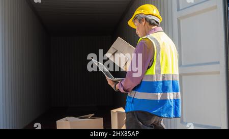 Old Manager with labtop computer inspector or Safety Supervisor in Container cargo CustomTerminal port concept import export transportation and logist Stock Photo