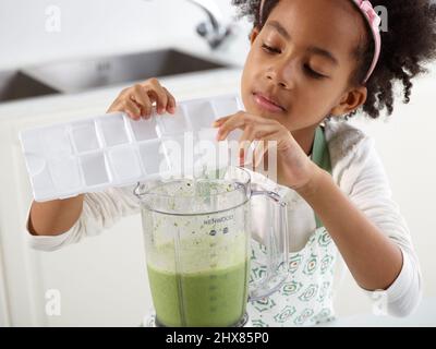 Green Smoothie - Adding ice to a blender filled with green smoothie (Step 3 of 3) Stock Photo