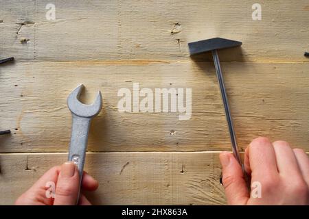 Wrench on wooden background. Hand holding a wrench and hammer Stock Photo