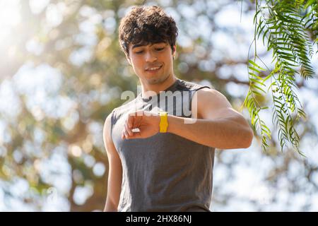 Young man doing sports look at the smart watch and laugh in the park Stock Photo