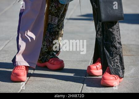 MILAN, ITALY - FEBRUARY 23, 2022: Women with red, pink plastic shoes before Marco Rambaldi fashion show, Milan Fashion Week street style Stock Photo