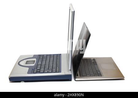 Close up of side by side open notebooks of different generations from old and heavy to modern and ultra light and thin on white background concept dev Stock Photo