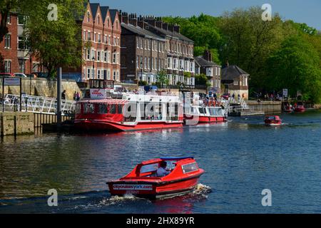 City Cruises boats & motorboat sailing on water - busy sunny picturesque River Ouse quayside moorings, King's Staith, York, North Yorkshire, England. Stock Photo