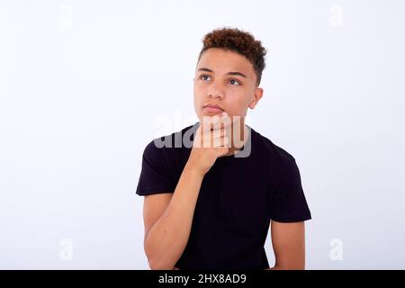 Boy think looking up, hold hand on chin Stock Photo