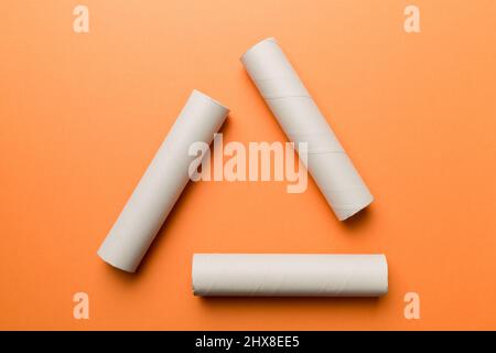 Empty toilet paper roll on colored background. Recyclable paper tube with metal plug end made of kraft paper or cardboard in the form of a recycling s Stock Photo