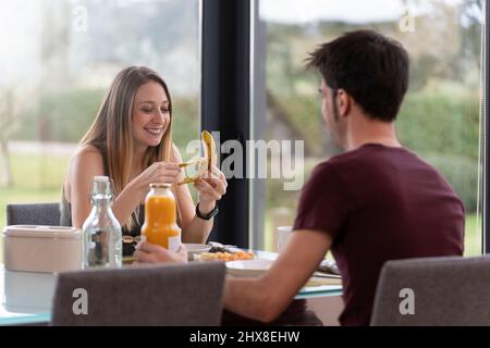 Young couple having breakfast in the living room at home near the garden Stock Photo