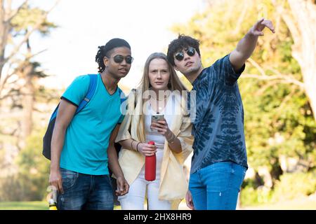 A couple of young tourists are lost and a young man is helping them in the park Stock Photo
