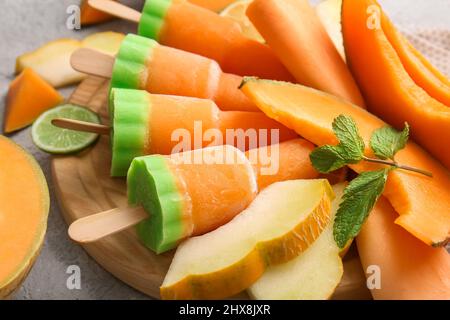 Board with tasty popsicles and melon pieces on light background Stock Photo