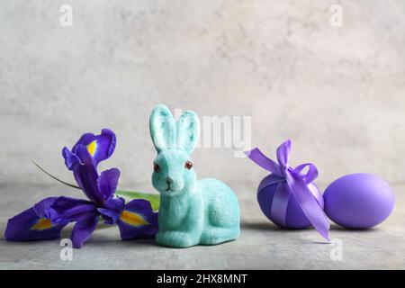 Cute Easter bunny with painted eggs and flower on light background Stock Photo