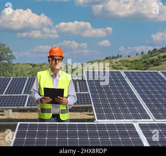 Electrician standing on a solar panel plant for renewable energy Stock Photo