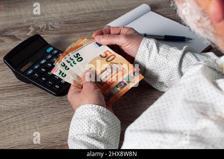 saving, finance, economy and housing concept - close up of man with calculator counting money and making notes at home Stock Photo