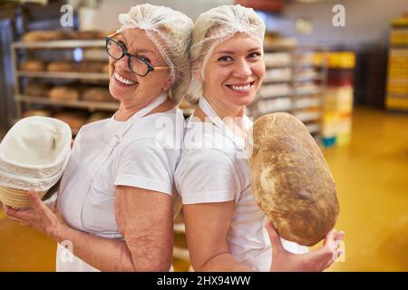Two bakers are happy together about healthy organic bread in the large bakery