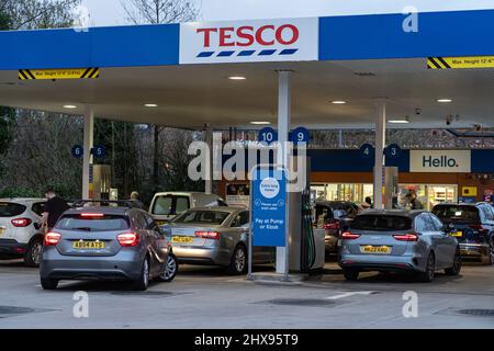 Wigan, UK: March 10, 2022: Queuing cars waiting to buy fuel at a Tesco petrol filling station as British drivers panic buy fuel Stock Photo