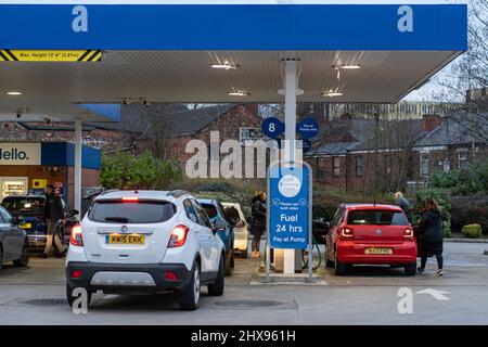 Wigan, UK: March 10, 2022: Queuing cars waiting to buy fuel at a Tesco petrol filling station as British drivers panic buy fuel Stock Photo