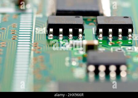 Close up detail of a computer circuit board, focusing on two integrated chips connected to the printed circuitry of a PCB board. Stock Photo