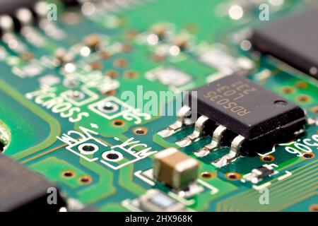 Close up detail of a computer circuit board, focusing on a single integrated chip connected to the printed circuitry of a PCB board. Stock Photo