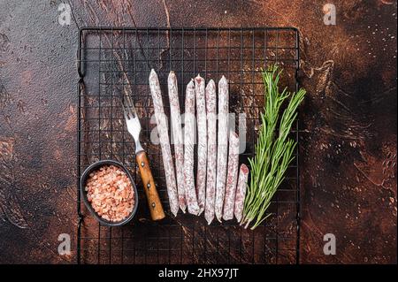 Fuet Catalan dry sausages with rosemary. Dark background. Top view Stock Photo