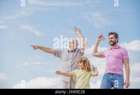 Men generation: grandfather father and grandson playing with toy plane outdoor on sky. Boy dreams of becoming a pilot. Stock Photo