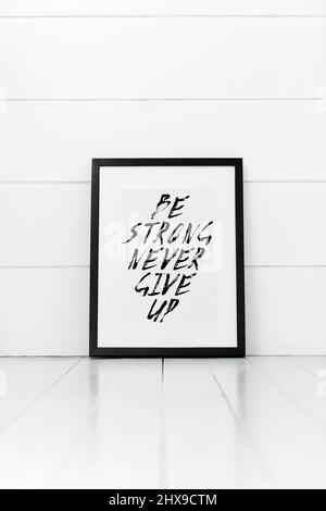Blank frame on a white background with quotation. Be strong never give up Stock Photo