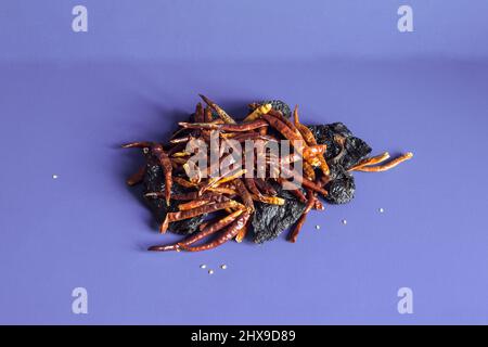 A pile of dehydrated chili peppers with dried ñora peppers on a textured color studio background. Still life and abstract decorations. Stock Photo