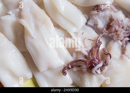 A bunch of fresh squids and raw tentacles on a plate. Healthy nutrition. Stock Photo