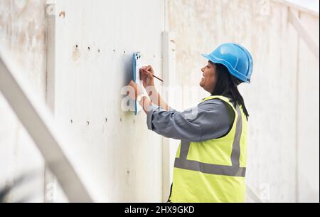 Tracking the job progress. Cropped shot of an attractive young female construction worker working on site. Stock Photo