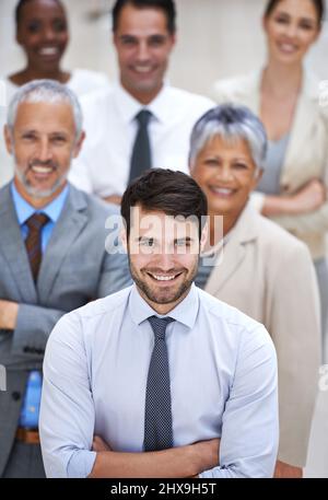 Why settle for mediocre when you can have amazing. Portrait of a smiling businessman surrounded by a group of his colleagues. Stock Photo