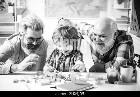 Grandfather father and cute little son having fun at home. Parenting childhood values weekend. Male multi generation portrait Playing Jenga. Stock Photo
