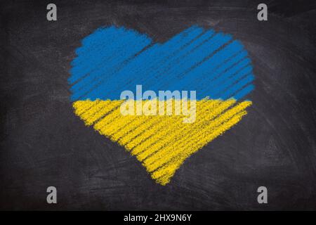 Heart shape chalk drawing on blackboard in Ukrainian Flag colors: blue and yellow. Stock Photo