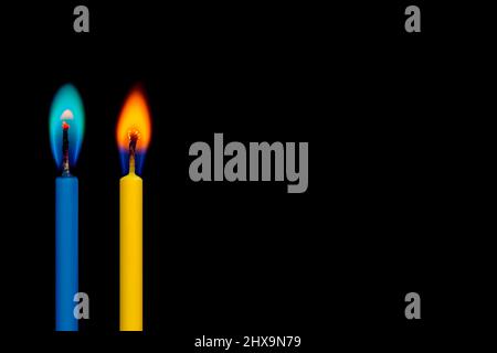 Two blue and yellow (in ukrainian flag colors) burning candles light on the black background Stock Photo