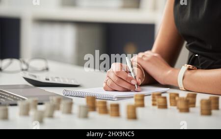 In the end, cents make dollars. Cropped shot of an unrecognizable businesswoman working out her finances with a calculator and a notepad in her office Stock Photo