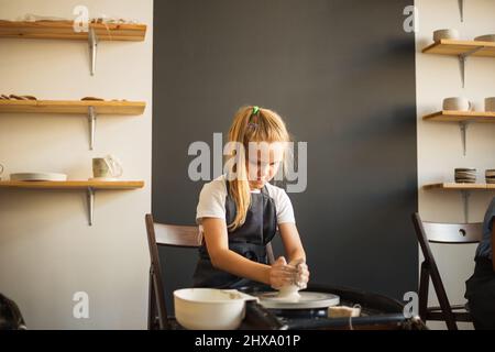 Portrait of girl working on pottery wheel and making clay pot. Stock Photo