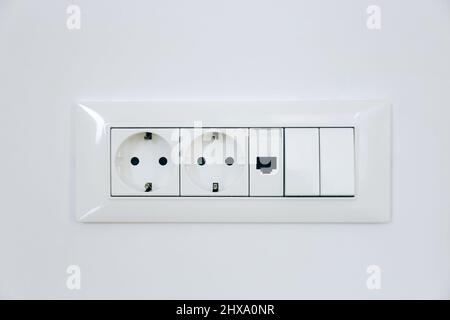 Electric light switch and socket on the white wall Stock Photo