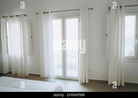 Three windows with white curtains in hotel room Stock Photo