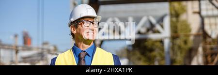 Joyful male worker using laptop outdoors at factory Stock Photo